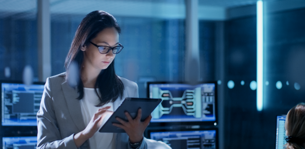 A bespectacled woman is looking down at a screen.