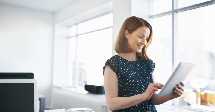 A woman holding a laptop is smiling while looking to her left.