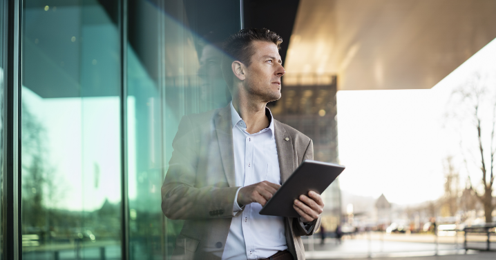 A man is looking to his left while holding a tablet.