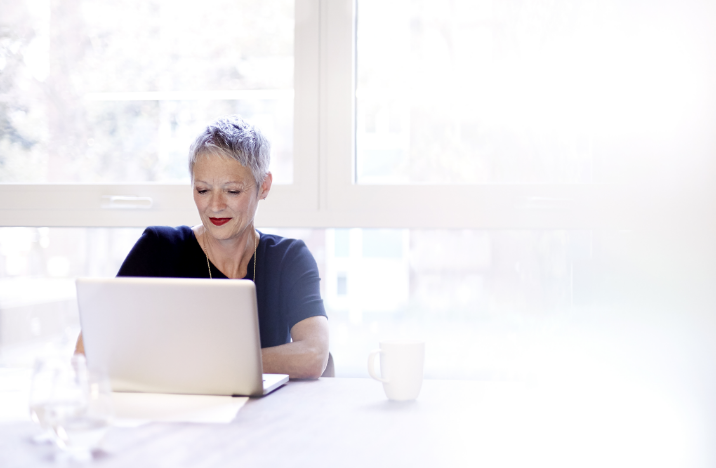 A short-haired woman is working on her laptop.