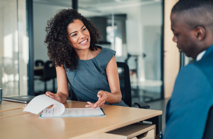 A man and a woman are conversing in a meeting room.