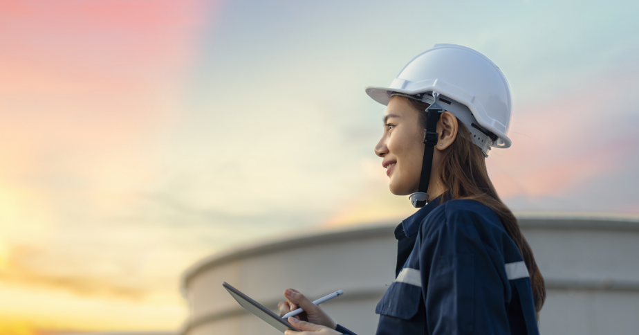 A woman wearing a helmet is holding a clipboard and smiling.