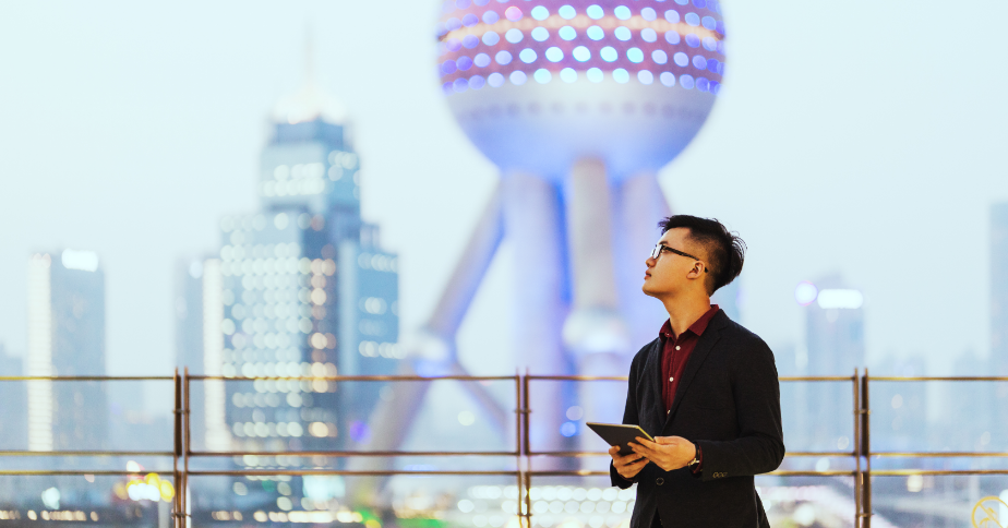 A man with a tablet in his hand is looking up at the skyline.